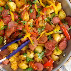 Kielbasa and Potatoes in a skillet being sautéed.