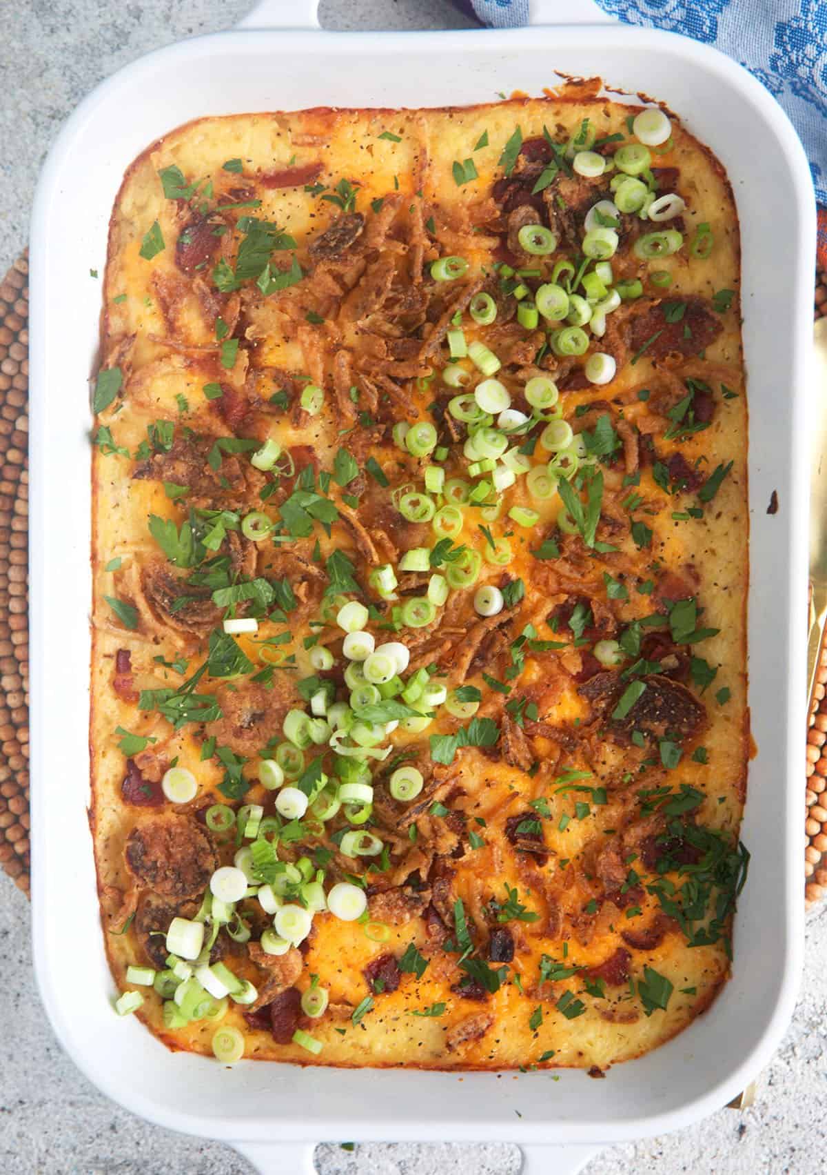 Loaded Mashed Potato Casserole in a white baking dish topped with chopped green onions.