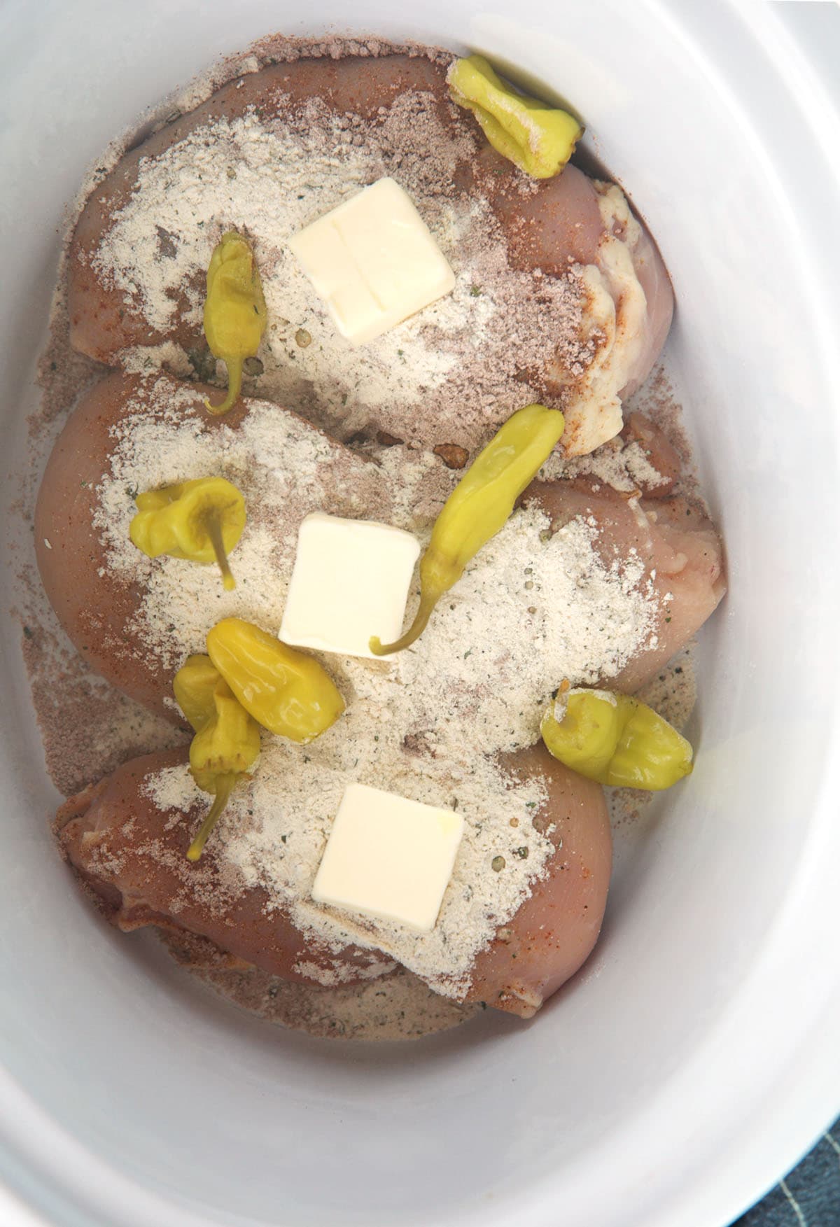 chicken topped with butter, ranch seasoning and pepperoncini peppers for Mississippi chicken