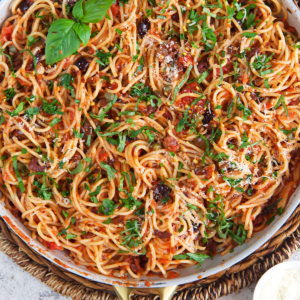 pasta puttanesca tossed in a skillet with the sauce.