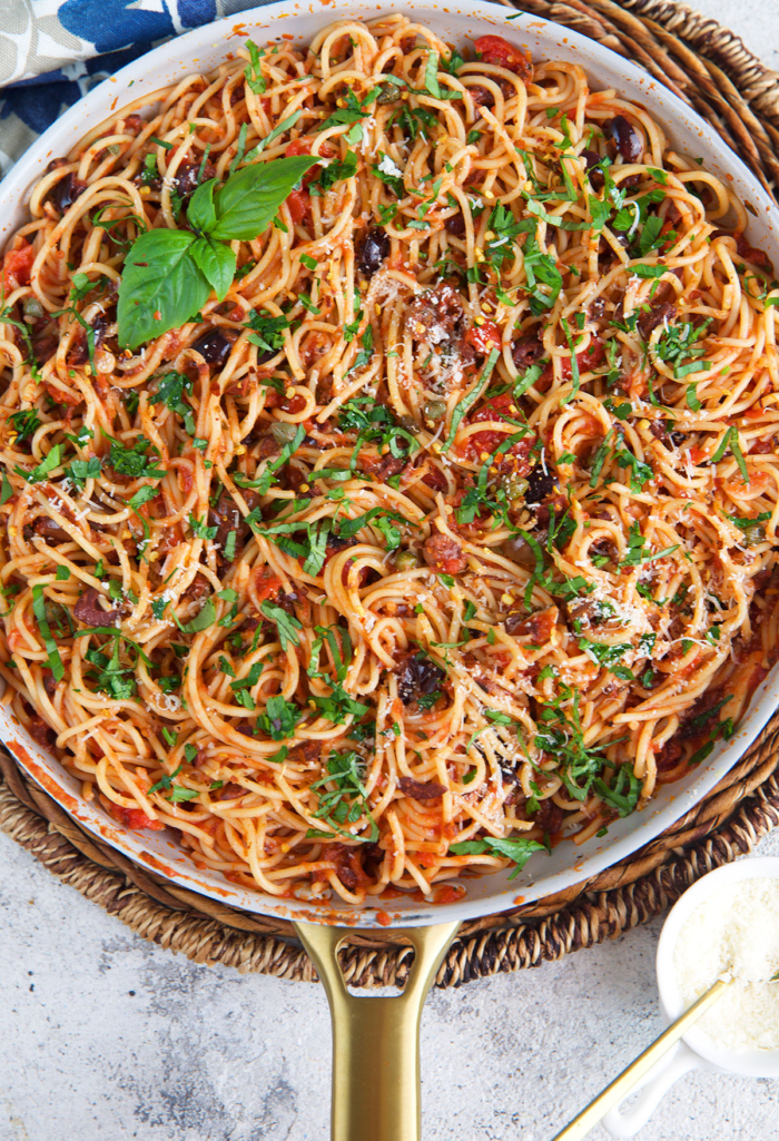 pasta puttanesca tossed in a skillet with the sauce.