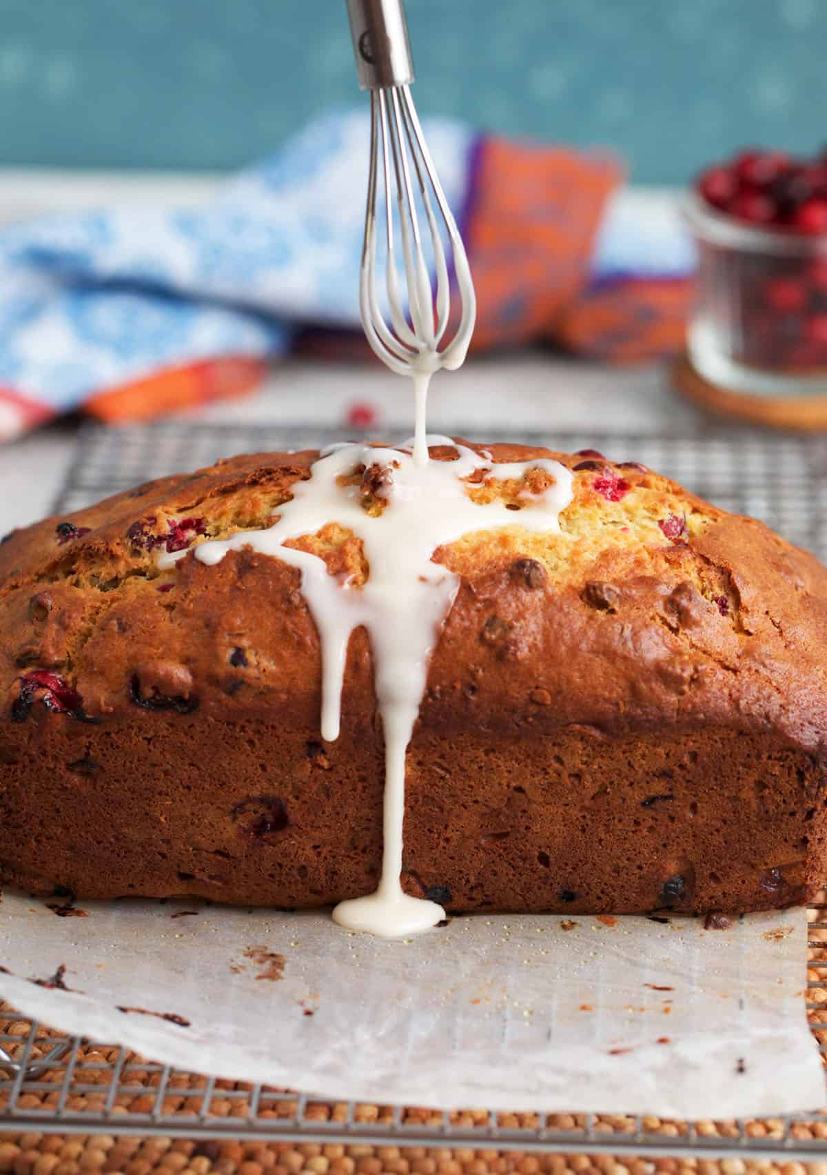 glaze being drizzled over cranberry quick bread