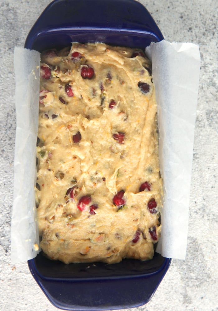 batter for cranberry bread in a loaf pan with a parchment sling