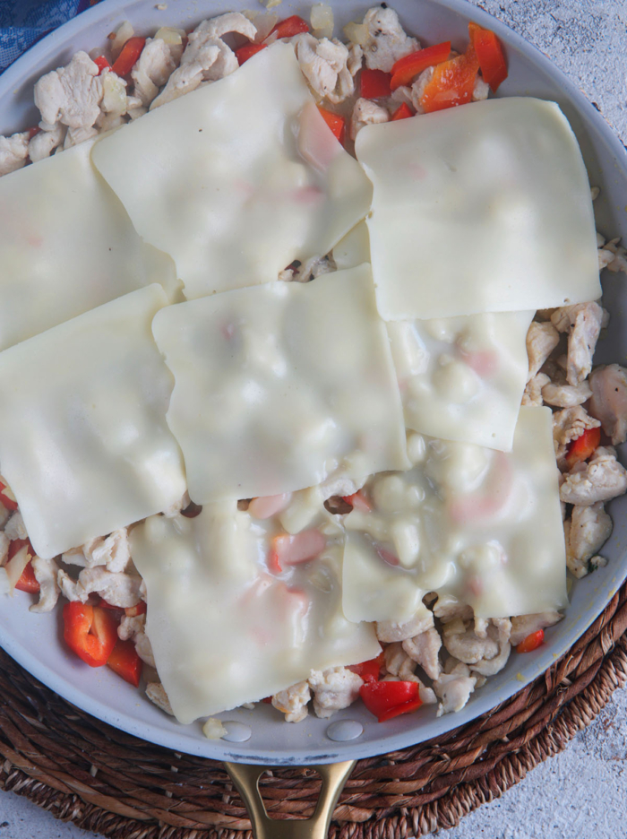 chicken cheesesteak mixture in a skillet with cheese melted on top