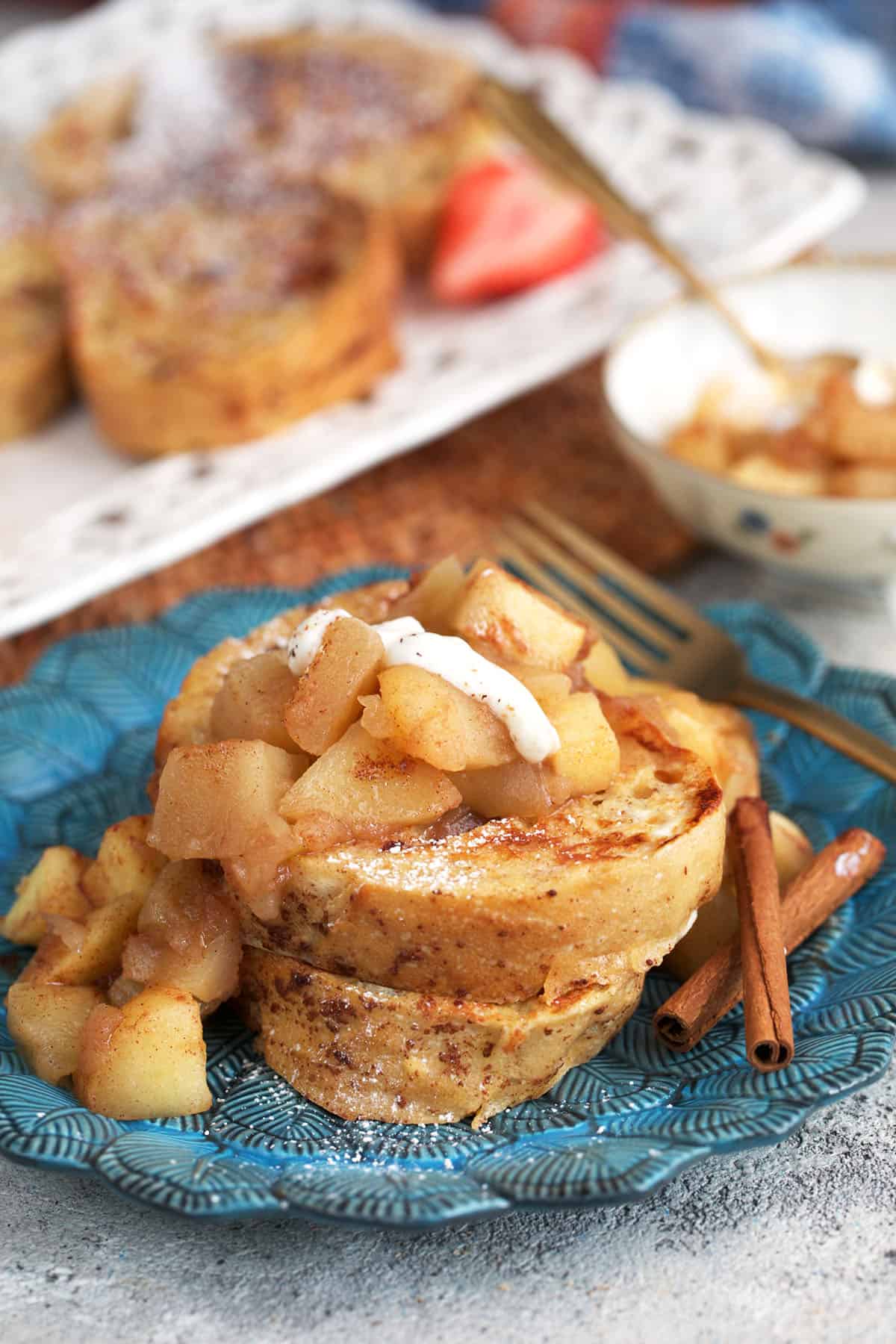 best sourdough French toast slices stacked on a blue plate with apples on top