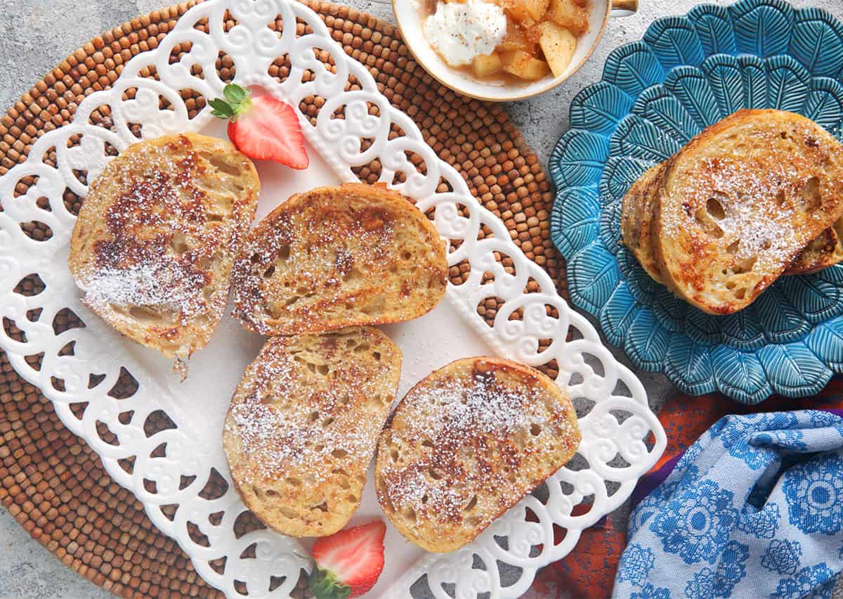 easy sourdough French toast on a white platter with strawberries for serving