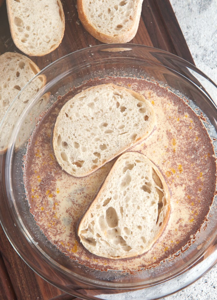 two slices of sourdough in a dish with French toast batter