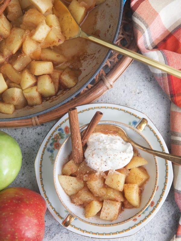 cooked apples in a china cup with a spoon.