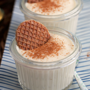 Vanilla pudding in glass cups with cinnamon on top and a mini stroopwafle