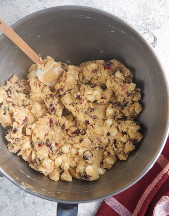 cookie dough in a steel mixing bowl with a spatula for white chocolate cranberry cookies