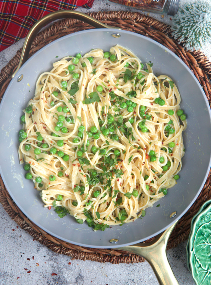 Christmas Fettuccine in a skillet topped with peas and parsley.