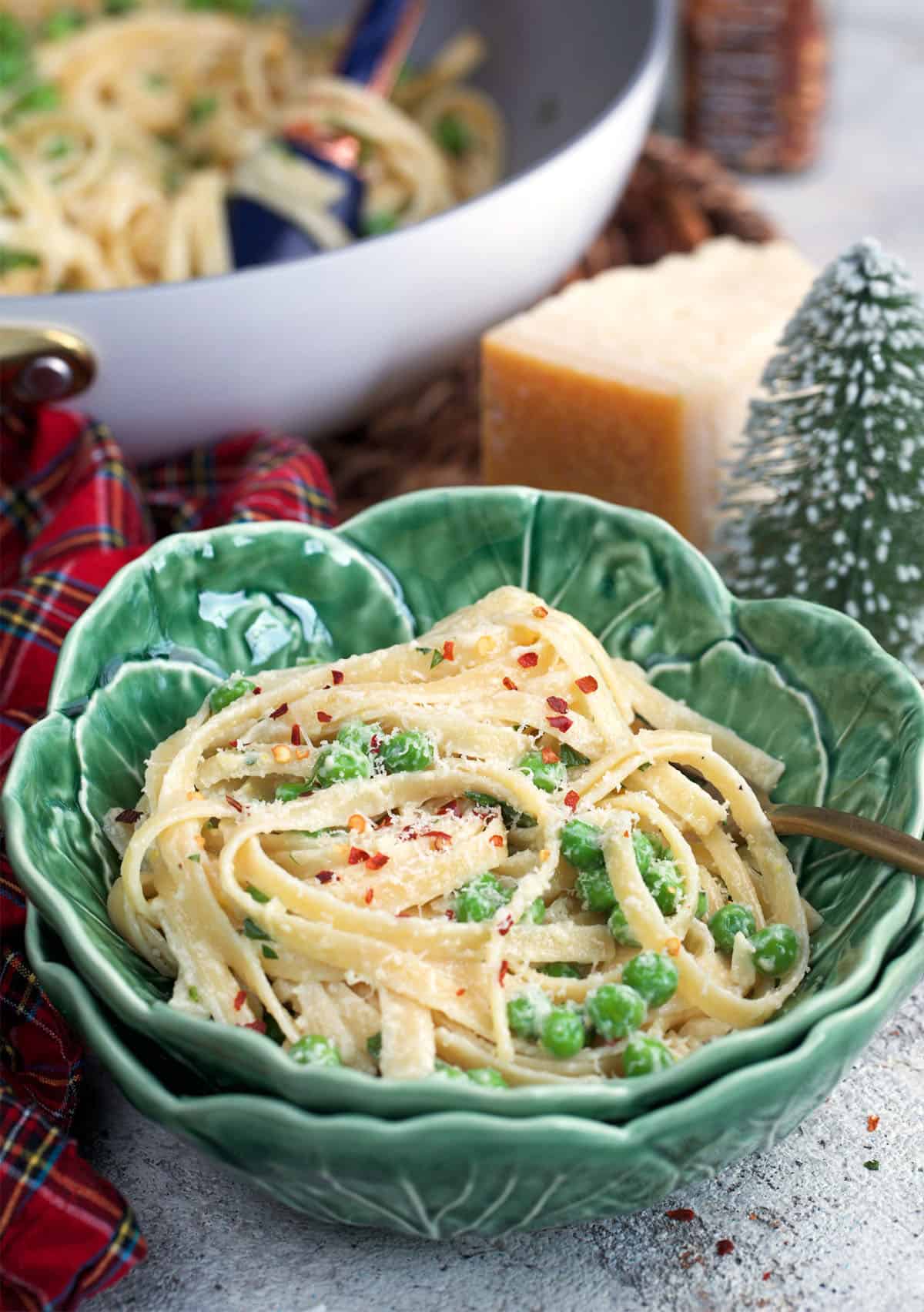 Christmas Fettuccine in a cabbage ware bowl with a skillet of fettuccine already behind it.
