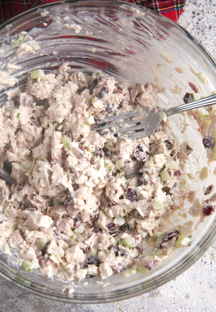 Cranberry chicken salad mixed together in a glass mixing bowl