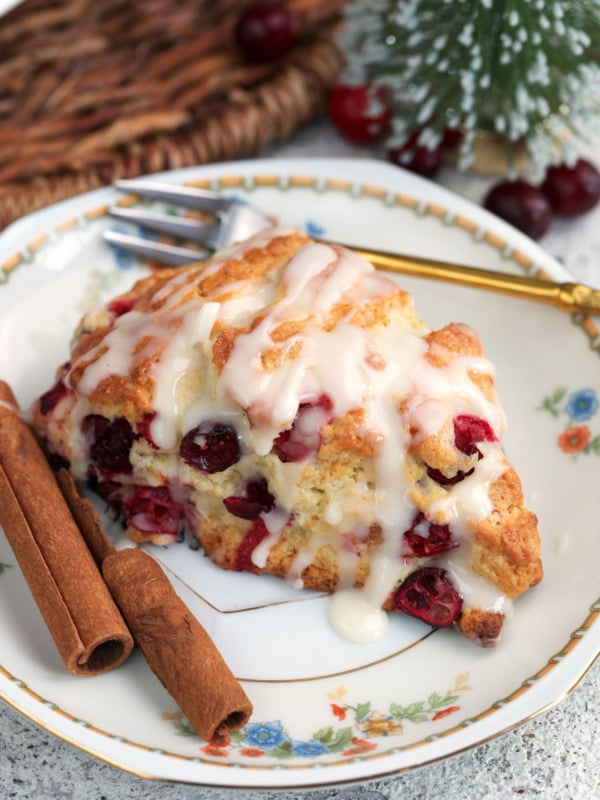 Cranberry Orange Scone on a white china plate with cinnamon sticks.
