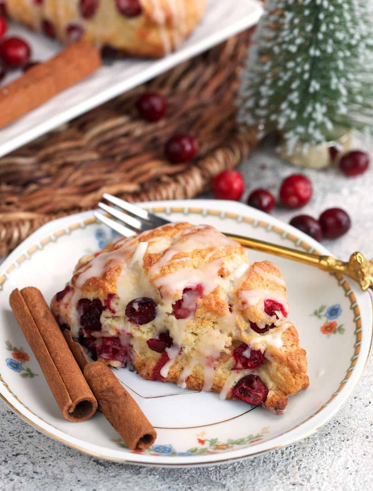 Cranberry Orange Scones on a plate with a gold fork and fresh cranberries.