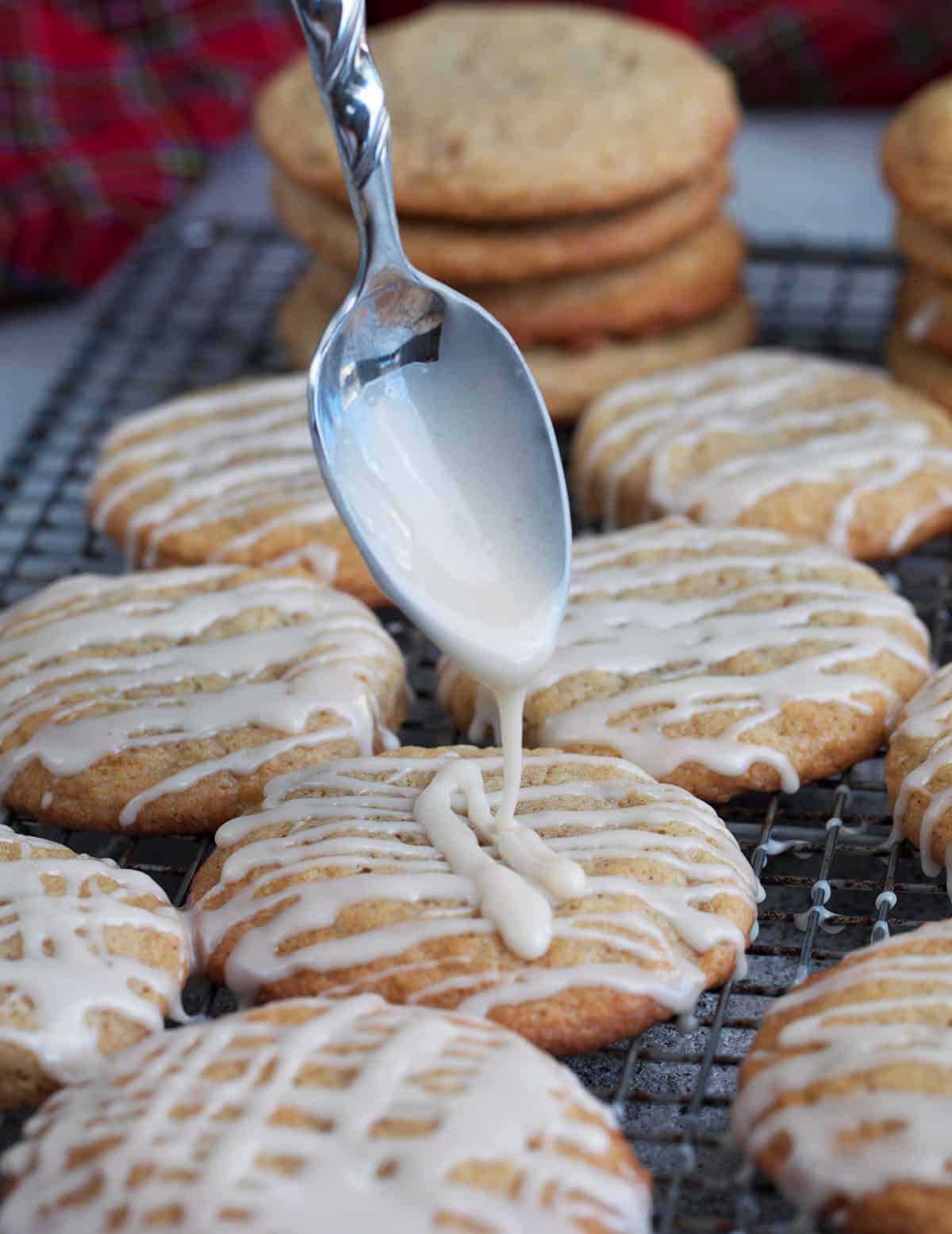 glaze being drizzled on an eggnog cookie with a spoon