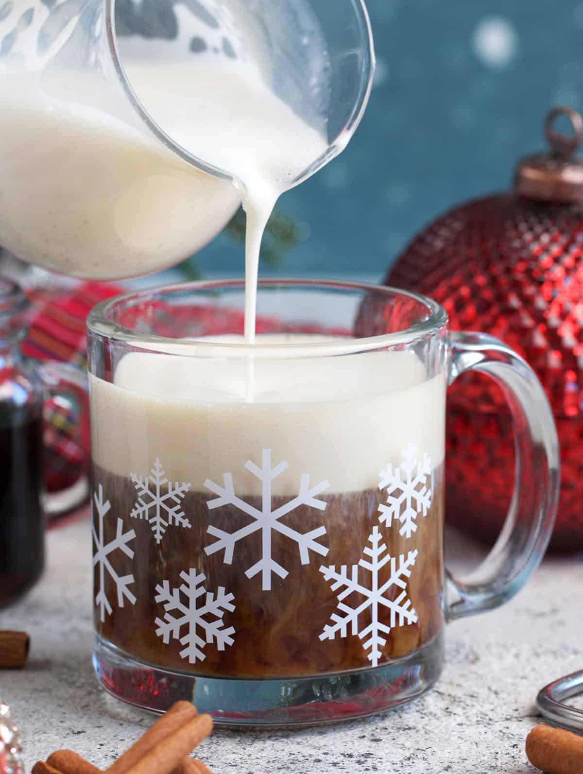 Eggnog being poured into a mug with coffee to make a homemade eggnog latte
