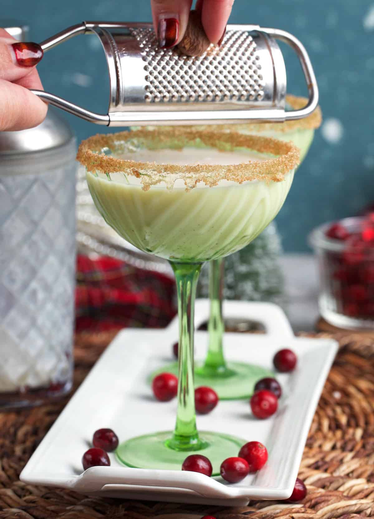 nutmeg being grated over a glass of eggnog martini