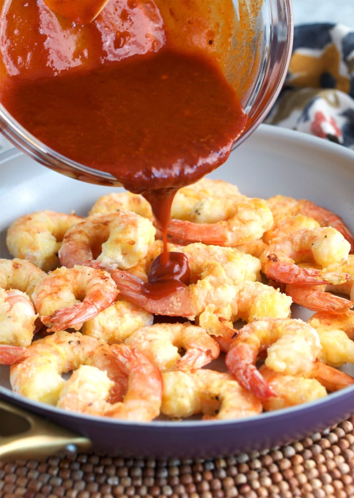 firecracker shrimp sauce being poured over crispy shrimp