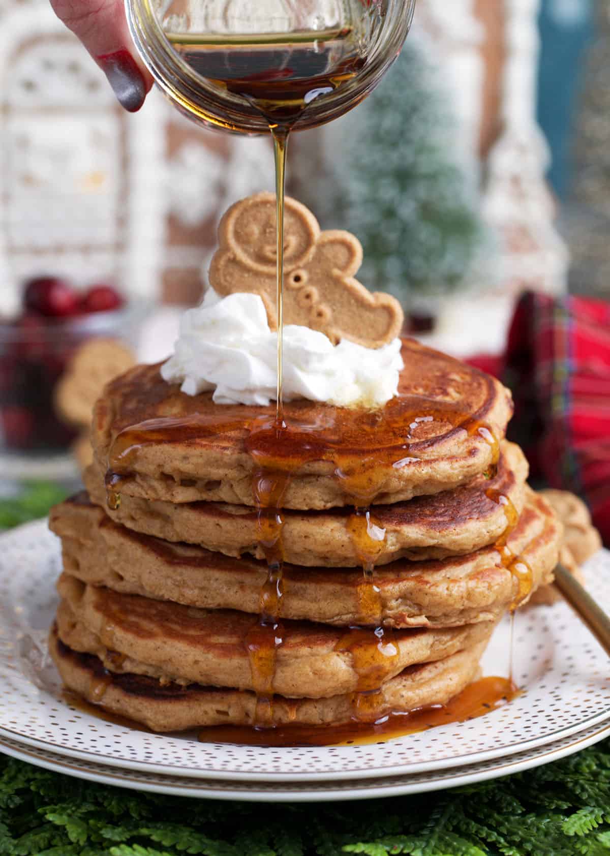 Gingerbread pancake stacked on a plate with whipped cream and a gingerbread man on top