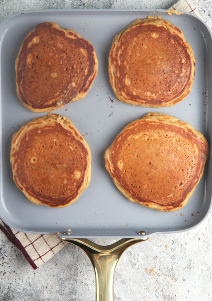 gingerbread pancakes cooking on a square griddle pan.