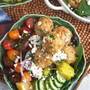 Greek chicken meatballs orzo bowls with cucumber, tomatoes and feta in a cabbage bowl.