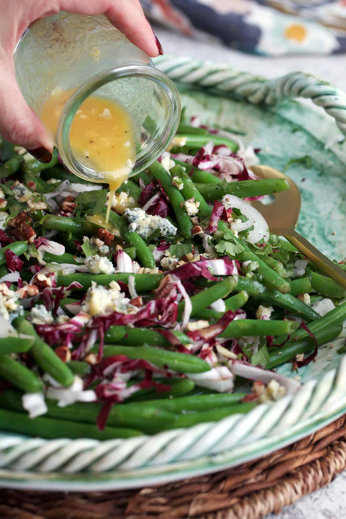 citrus vinaigrette being poured over a green bean and radicchio salad