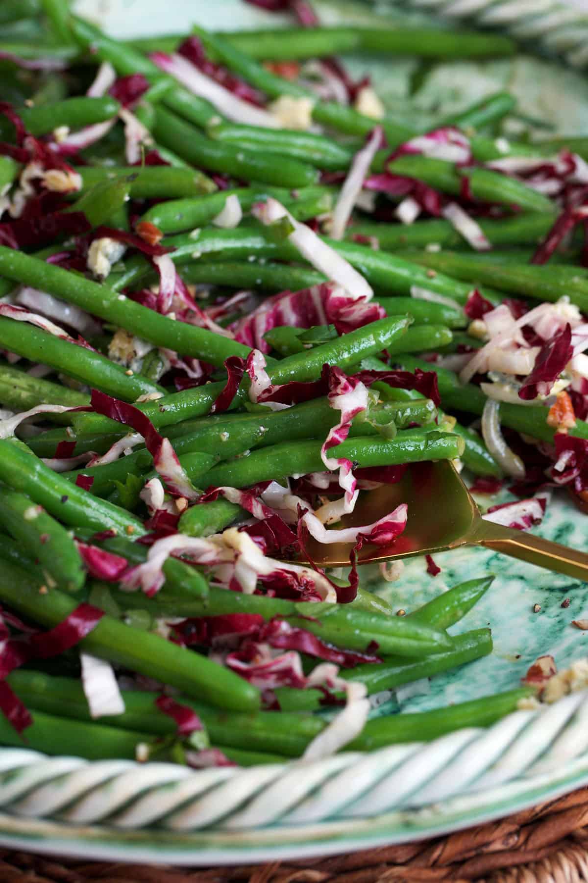 green bean radicchio salad with blue cheese and walnuts in a serving bowl with a gold spoon.