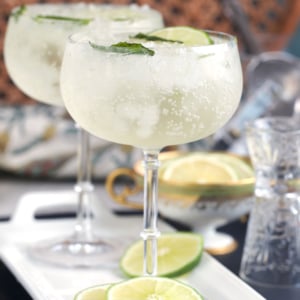 Two glasses with Hugo spritz on a white tray with lime slices
