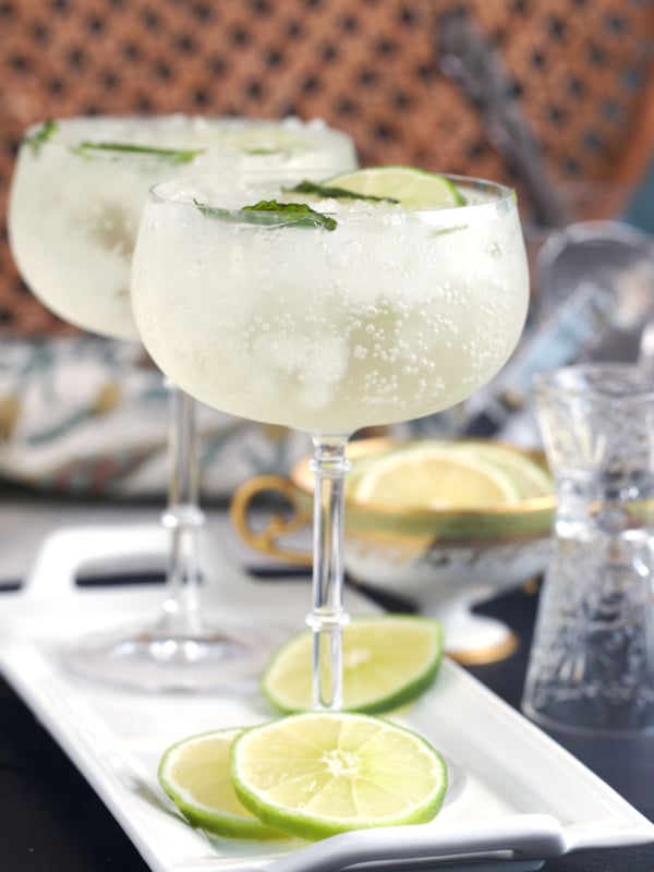 Two glasses with Hugo spritz on a white tray with lime slices
