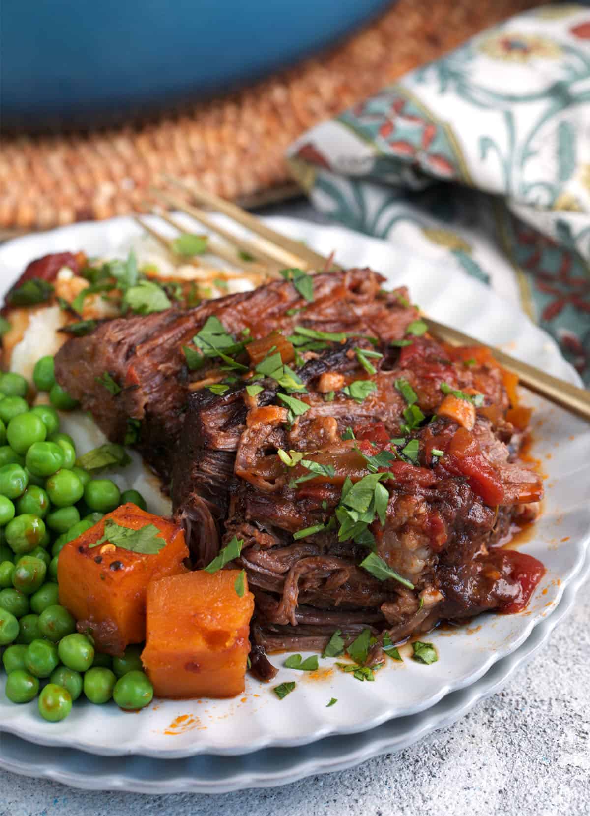 The best dutch oven pot roast sliced on a plate with peas