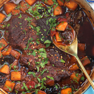 Dutch Oven Pot Roast with a gold serving spoon and butternut squash