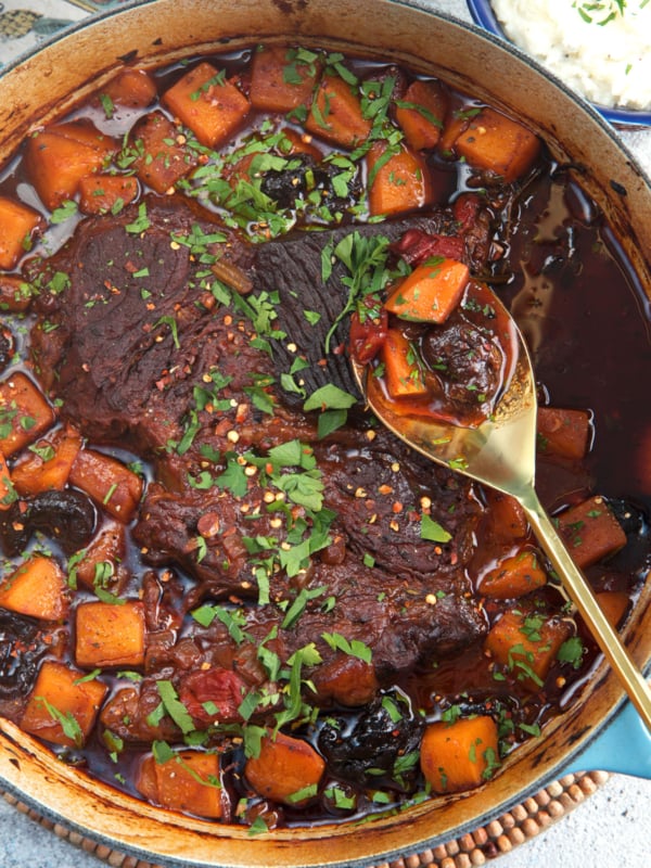 Dutch Oven Pot Roast with a gold serving spoon and butternut squash