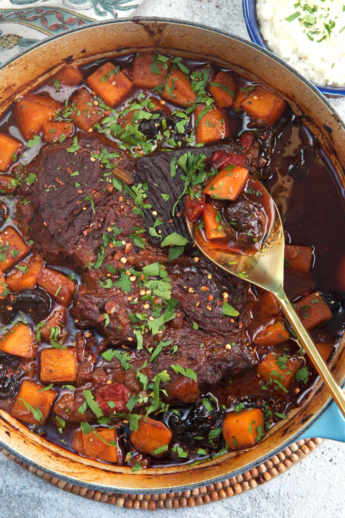 Dutch Oven Pot Roast with a gold serving spoon and butternut squash
