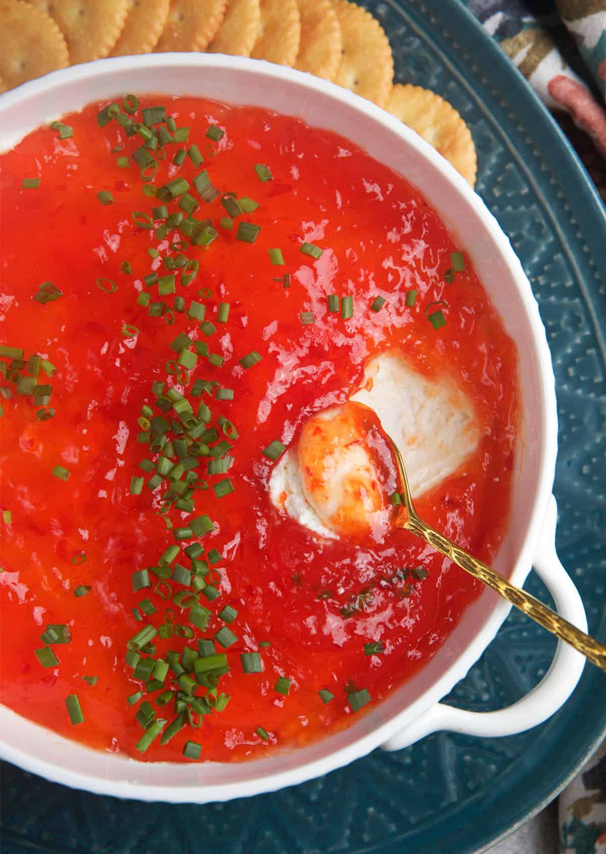 Pepper Jelly Cream Cheese Dip in a white dish with a spoon for serving.