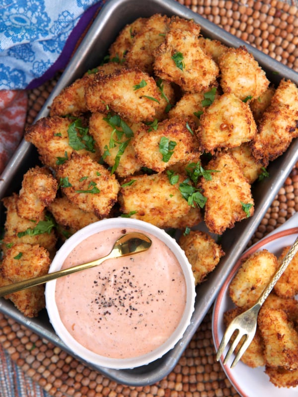 Air Fryer chicken Nuggets on a serving tray with a bowl of dipping sauce.