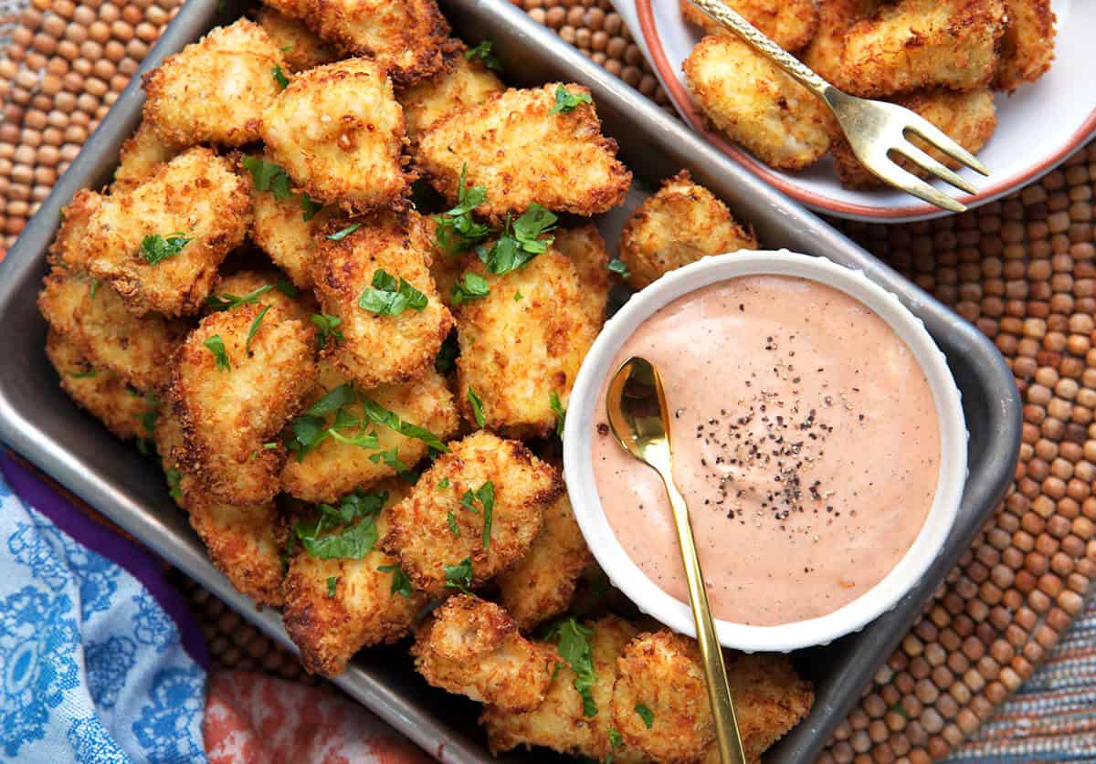 Air Fryer chicken nuggets serve in a pan with a bowl of sauce.