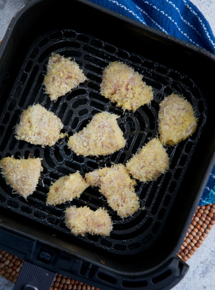 chicken nuggets ready to be fried in the basket of an air fryer.