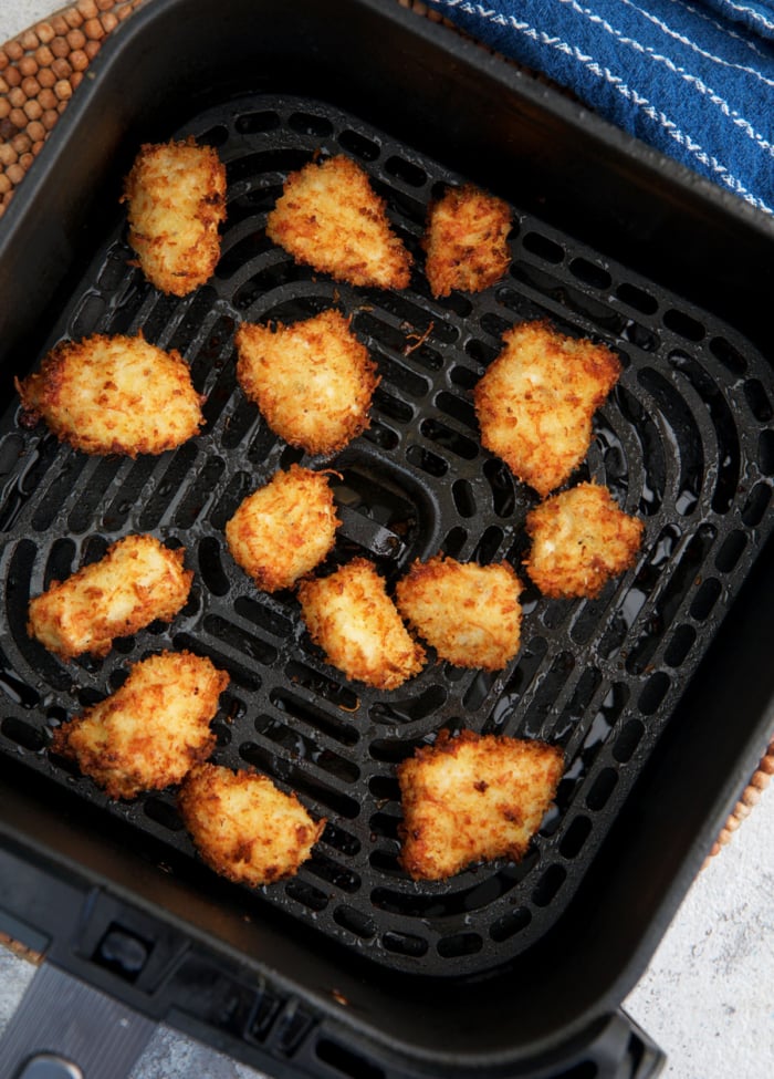 Chicken nuggets in an air fryer basket crispy and golden brown.