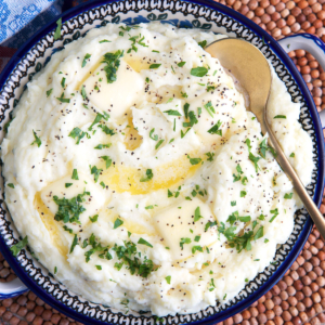 Boursin cheese mashed potatoes in a serving bowl with a gold serving spoon