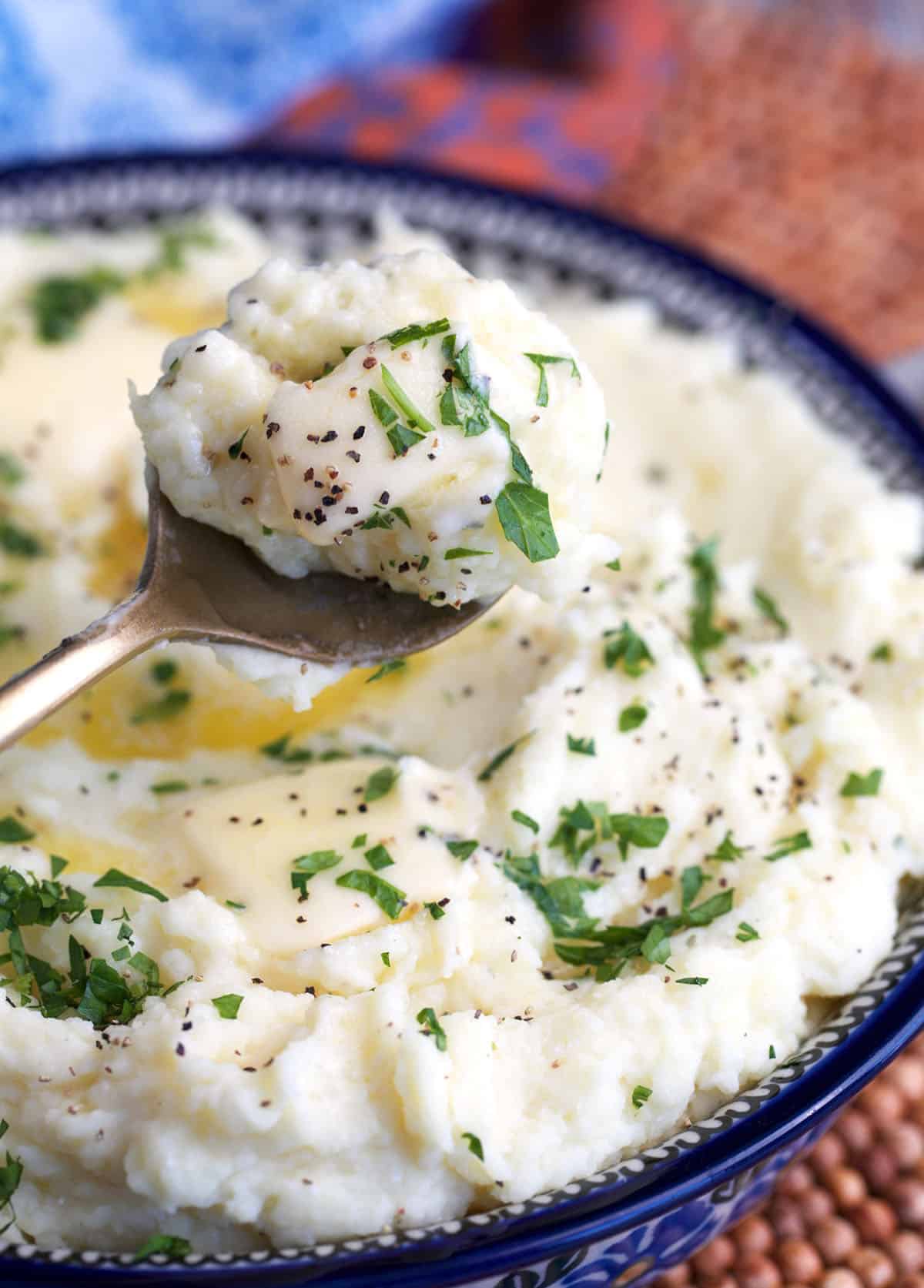 Boursin mashed potatoes in a serving bowl with a scoop of potatoes on a spoon.