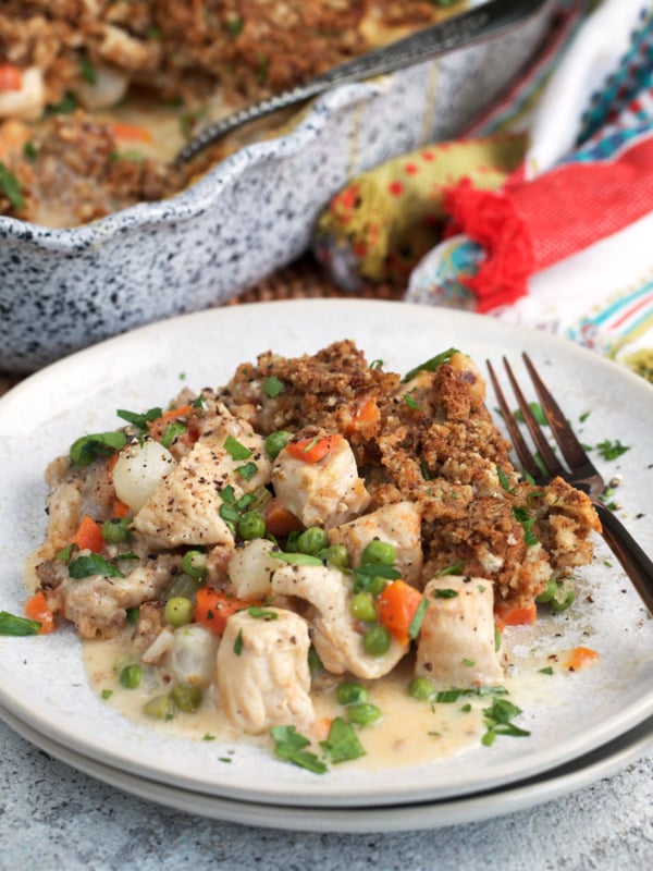 Chicken and Stuffing Casserole on a plate with a baking dish in the background.