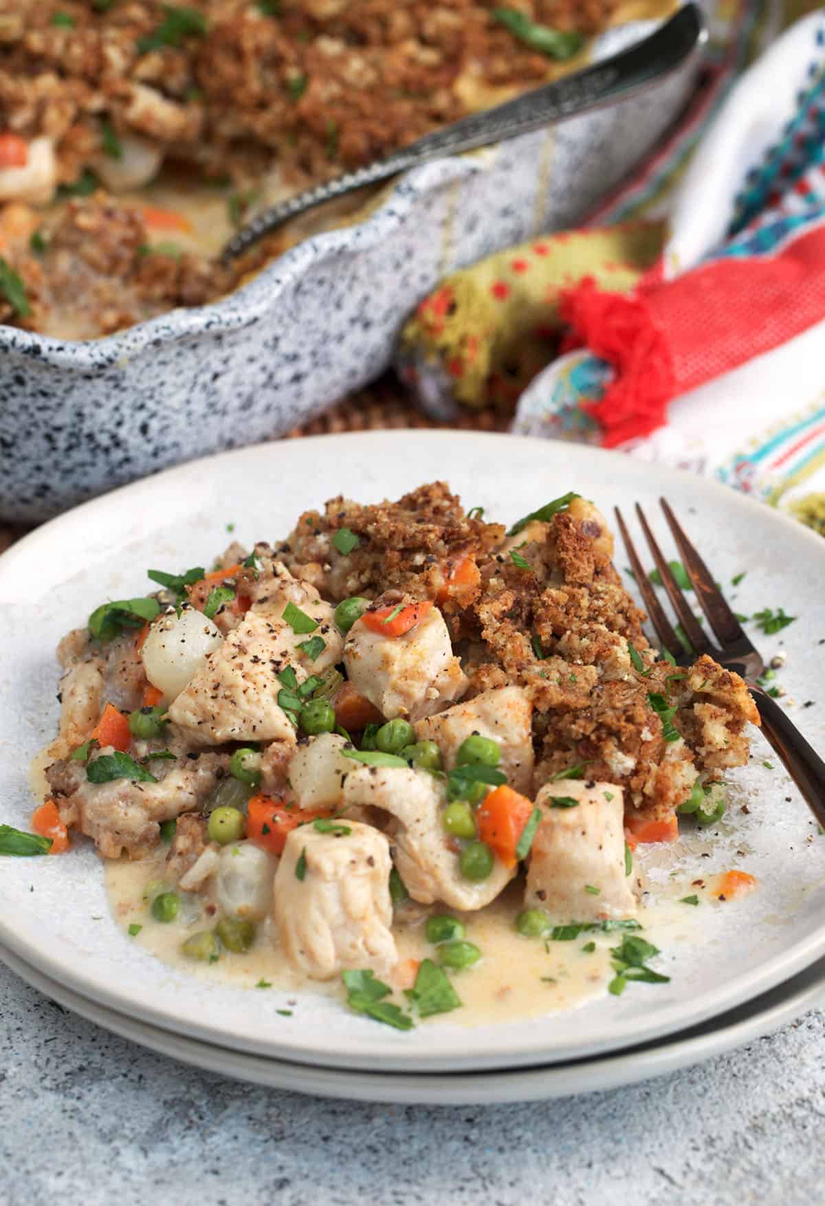 Chicken and Stuffing Casserole on a plate with a baking dish in the background.