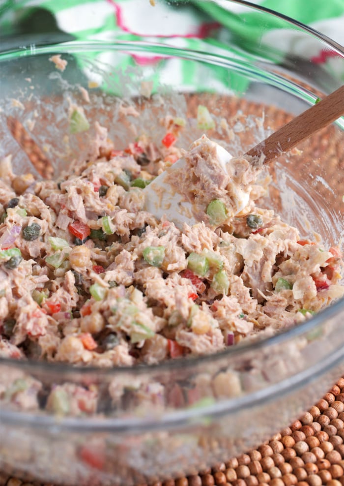 finished tuna chickpea salad in a glass bowl with a wooden spoon.