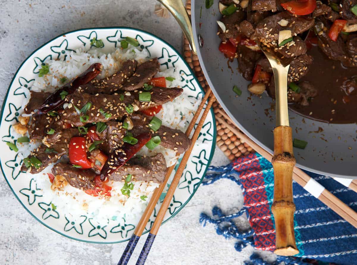 Kung Pao Beef Being served over a rice on a plate