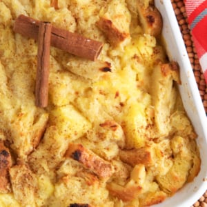Baked Pineapple Stuffing in a white casserole dish topped with cinnamon sticks.