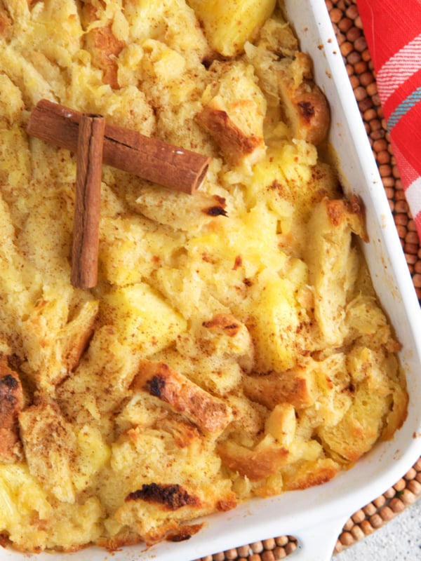 Baked Pineapple Stuffing in a white casserole dish topped with cinnamon sticks.