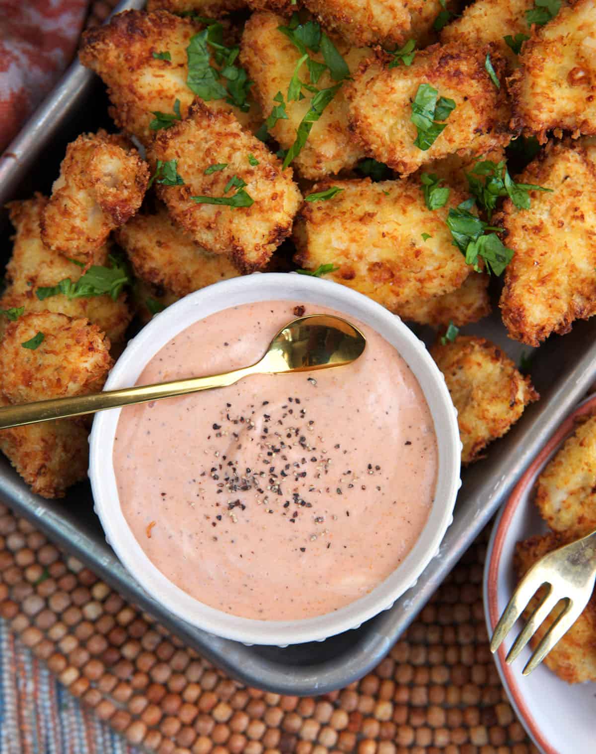 Raising Canes Sauce recipe in a white bowl with a tray of chicken nuggets