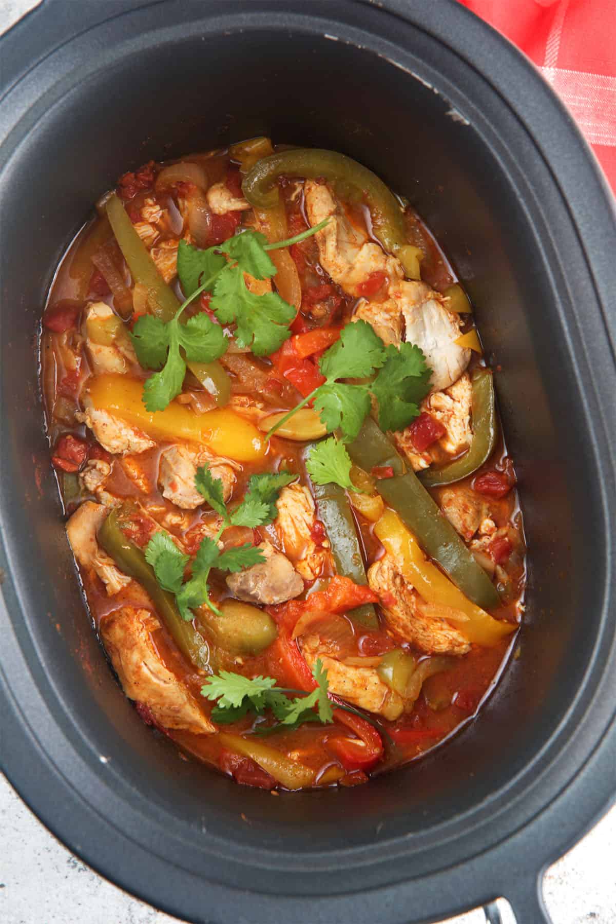 Slow cooker chicken fajitas in a black slow cooker.