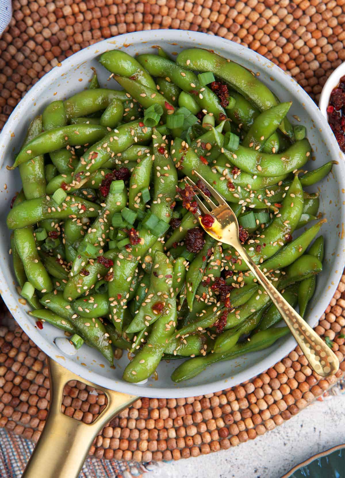 Spicy Edamame in a skillet with a gold fork.